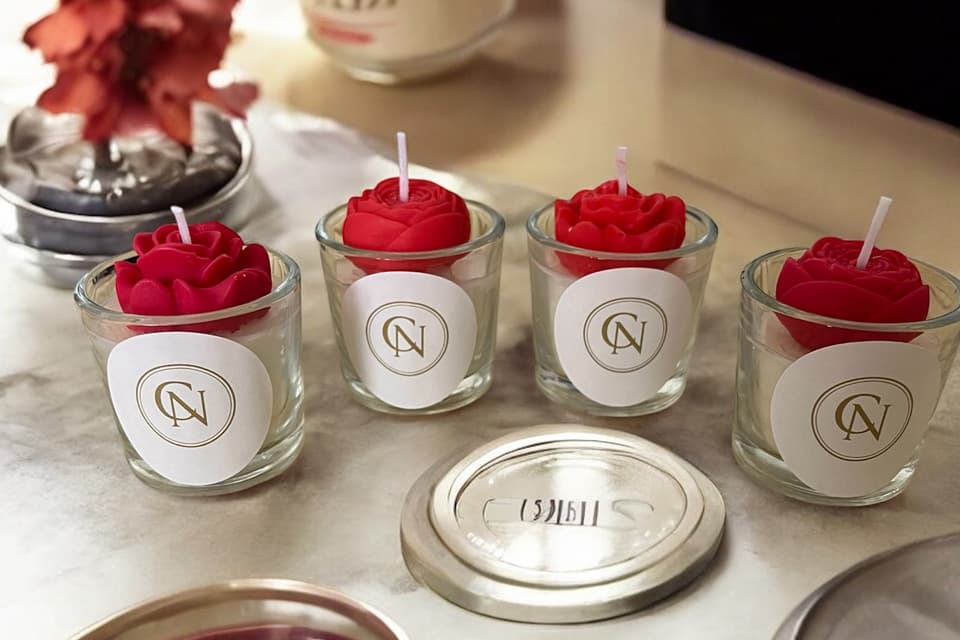 Bougies moulées rouges en forme de rose, présentées dans des contenants en verre avec étiquette Ceranatura